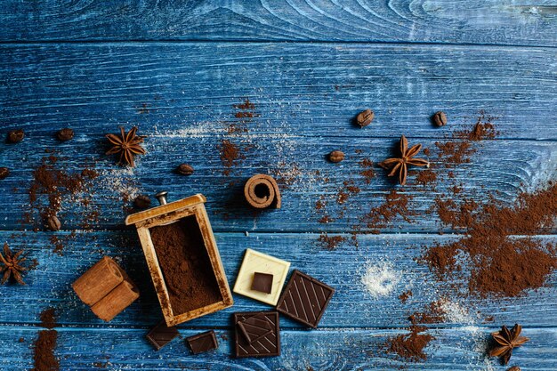 La cannelle, le café d'étoiles d'anis et les morceaux de chocolat se trouvent sur un fond de planche de bois peint turquoise coloré