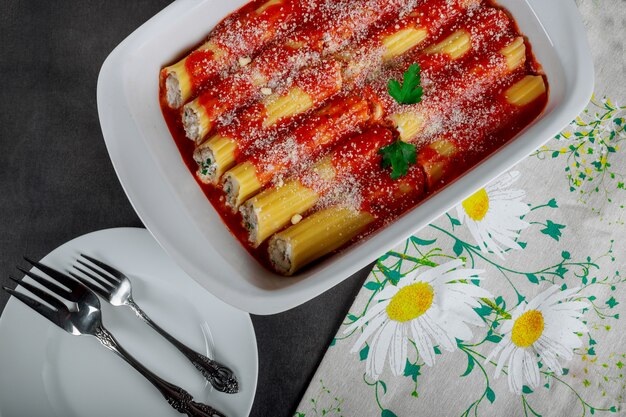 Cannellonis de pâtes italiennes à la viande, sauce tomate et fromage sur table