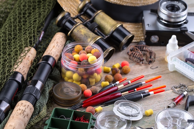 Cannes à pêche et spinnings dans la composition avec des accessoires pour la pêche sur l'ancienne surface sur la table