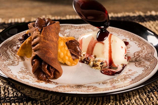 Photo cannoli avec glace, chocolat et amandes dans l'assiette