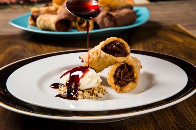 Cannoli avec glace, chocolat et amandes dans l'assiette