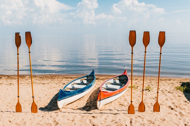 Canoë sur la plage en journée d'été ensoleillée sur une mer floue avec fond de nuages. Kayak avec des pagaies en bois sur la côte de la mer Méditerranée.