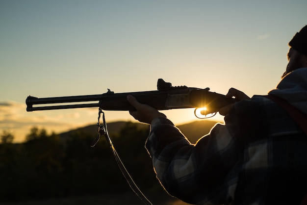 Canon d'une arme à feu Fusil Hunter Silhouetté dans Beautiful Sunset Hunter avec fusil puissant avec portée Spotting Animals Copier l'espace pour le texte