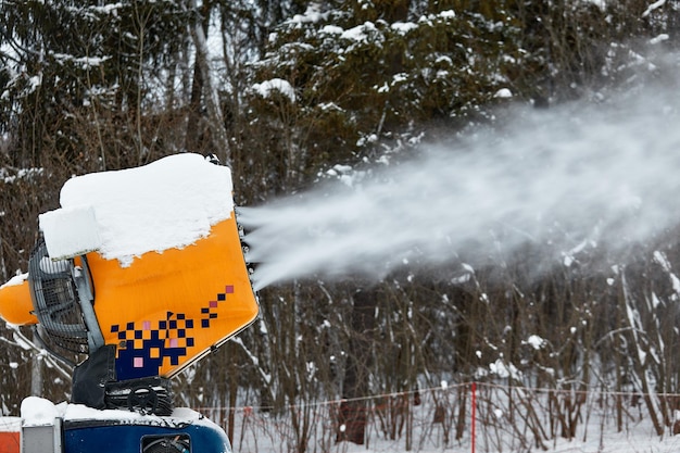 Canon à neige pulvérisant une nouvelle couche de neige sur les pistes de ski.