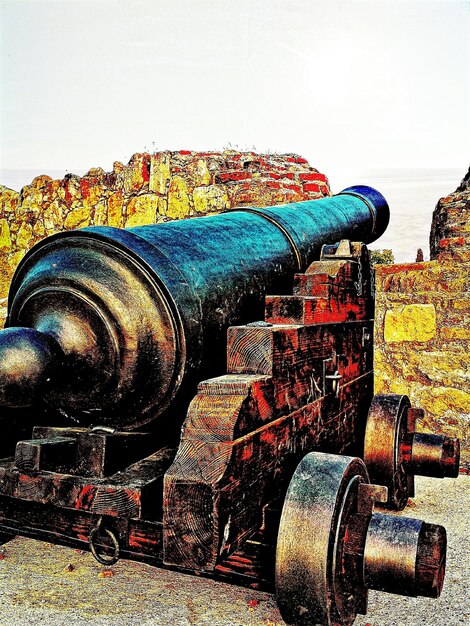 Photo canon rouillé par le mur d'entourage contre le ciel