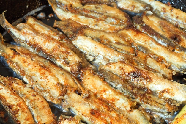 Capelan de poisson frit sur poêle noire