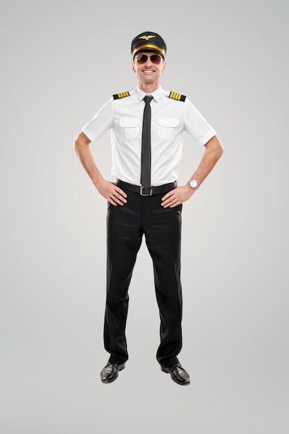 Capitaine de compagnie aérienne souriant avec les mains sur les hanches