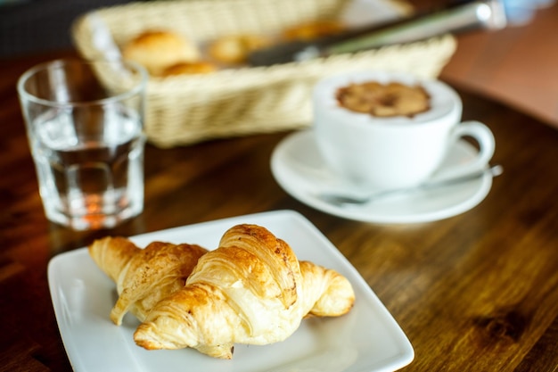 Photo cappuccino et croissant avec de l'eau