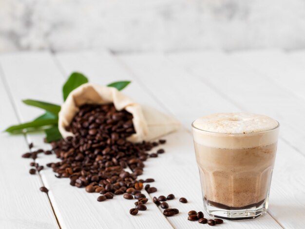 Cappuccino dans un verre sur une table en bois blanc