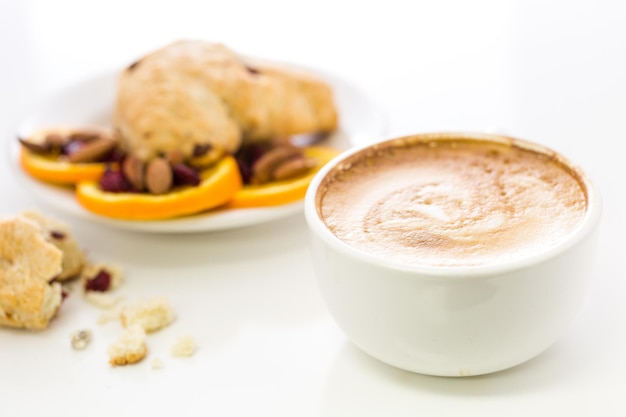 Cappuccino avec scone à l'orange et aux canneberges fraîches pour le petit-déjeuner.