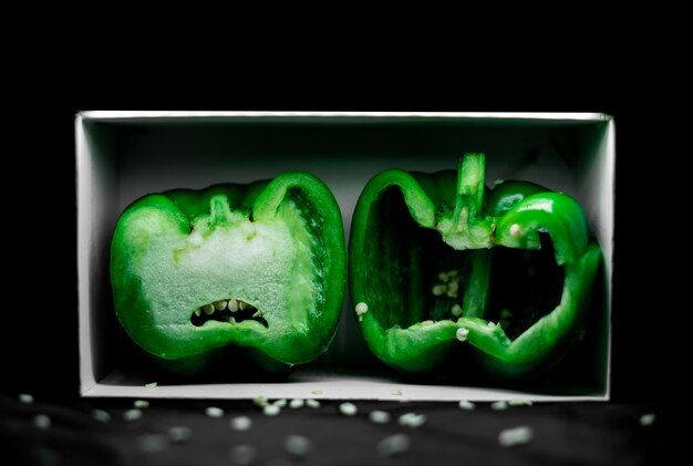 Capsicum vert avec un fond noir foncé dans une boîte avec des expressions