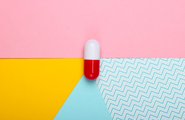 Capsule pilule sur fond pastel coloré. Vue de dessus