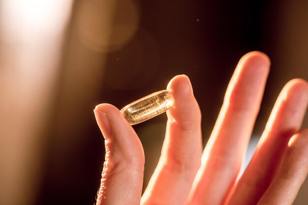 Capsule de pilule avec une solution d'huile transparente dans les doigts Panacée pour les virus et les maladies