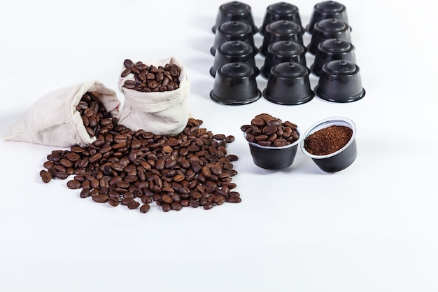 Capsules de café moulu pour le café, grains de café torréfiés dans des sacs de chiffon, grains de café torréfiés sur fond blanc.