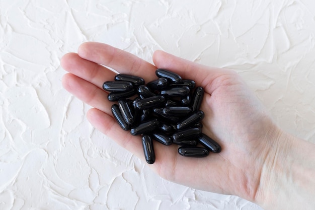 Capsules de charbon de noix de coco activé noir dans la main d'une femme libre Santé et bien-être automédication