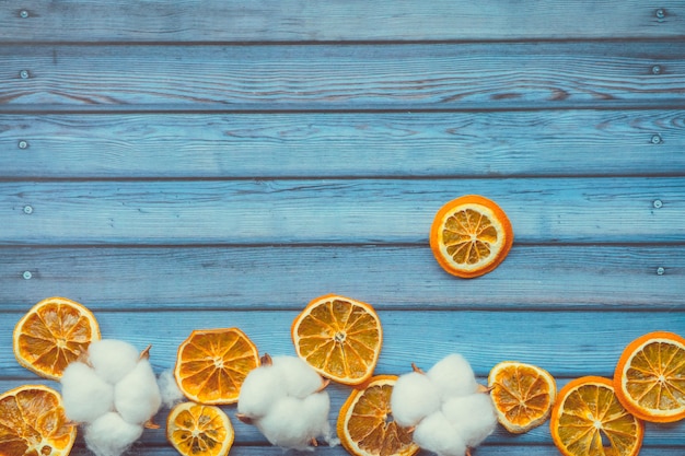 Capsules de coton et oranges tranchées sur une table en bois bleue