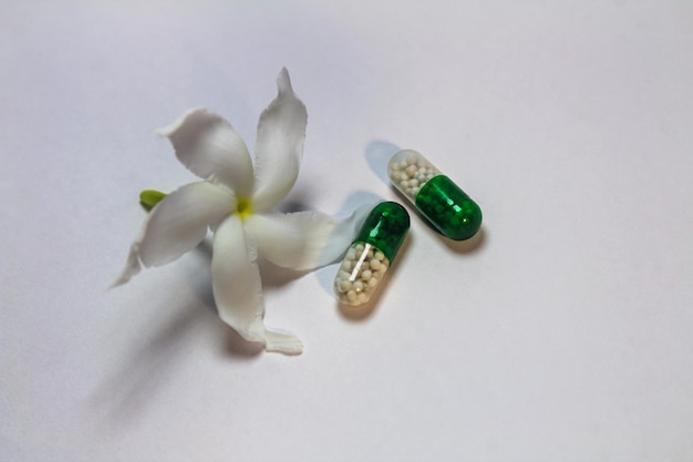 Capsules avec fleur de jasmin sampaguita sur fond blanc