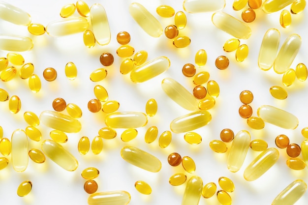 Capsules d'huile de poisson avec oméga-3 et vitamines sur fond blanc