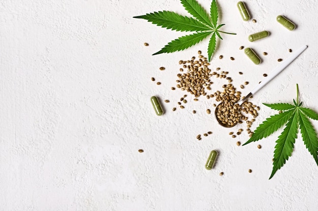 Capsules de médecine du cannabis Feuilles et graines vertes de chanvre sur fond blanc Anesthésie et concept de cannabis à effet sédatif