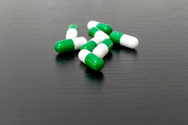 Capsules de médecine verte et blanche sur fond noir