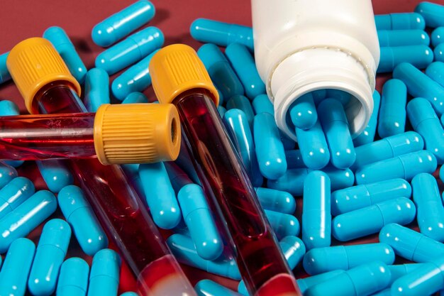 capsules de médicament bleues et bouteille blanche et éprouvette de sang