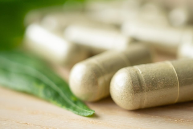 Capsules de phytothérapie avec feuille d'Andrographis paniculata sur table en bois