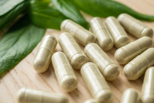 Capsules de phytothérapie avec feuille d'Andrographis paniculata sur table en bois