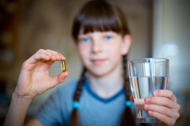 Capsules, Pilules Dans Une Main, Un Verre D'eau Dans L'autre.