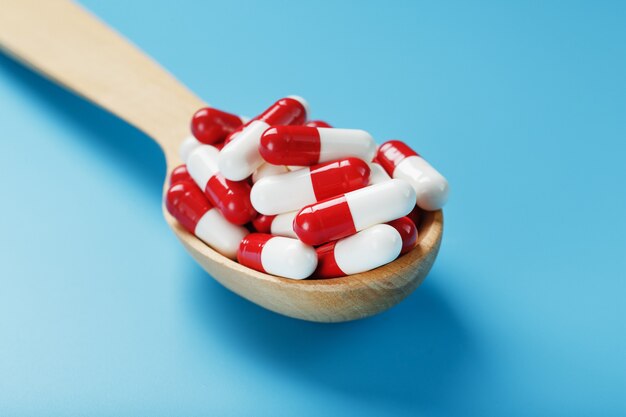 Capsules de pilules rouges et blanches sur fond bleu.