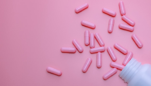 Capsules roses étalées sur une bouteille de médicament en plastique L'assurance-maladie des femmes et le cancer du sein