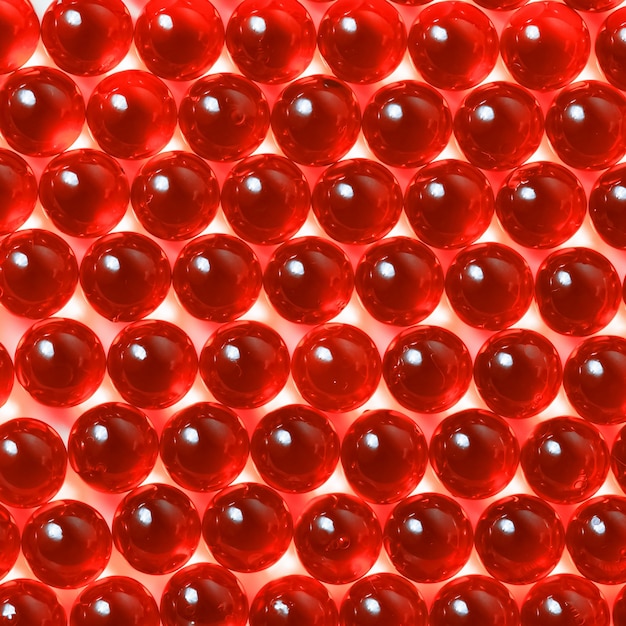 Capsules rouges sur un gros plan de fond blanc.