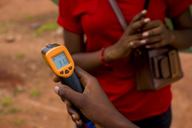 Capture d'écran d'une femme africaine tenant un thermomètre infrarouge portable