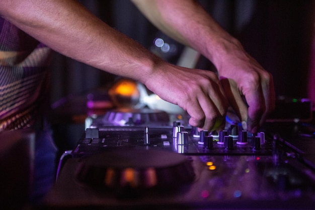 Capture de mise au point sélective du contrôleur DJ noir avec les mains du DJ