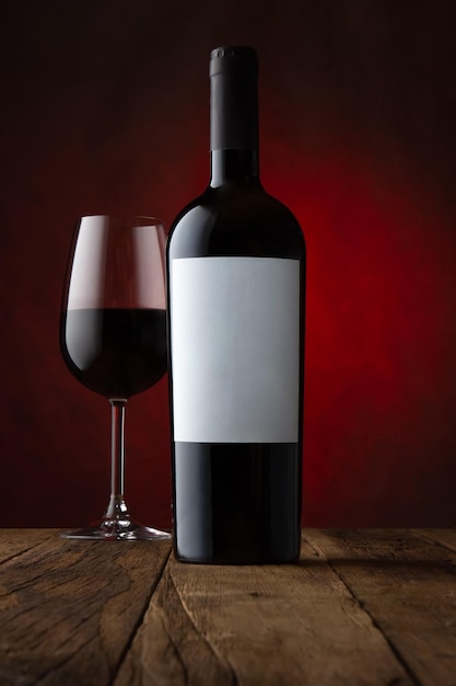 Photo capture promotionnelle d'un verre et d'une bouteille de vin rouge avec une étiquette vide et une maquette de fond brun rouillé