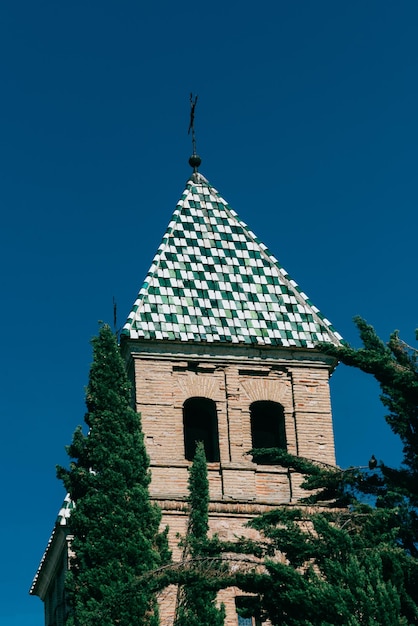 Capture verticale en angle bas d'une belle église à Tolède en Espagne avec un toit de tuiles vertes et blanches