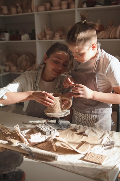 Photo capture verticale d'une charmante femme appréciant la décoration de céramiques avec son jeune fils à l'atelier d'art