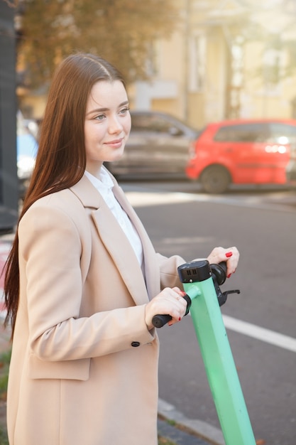 Capture verticale d'une charmante jeune femme appréciant la conduite d'un scooter électrique dans la ville