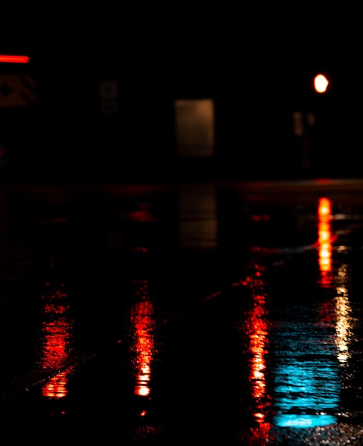 Capture verticale des lumières rouges reflétées sur le sol mouillé pendant la pluie la nuit