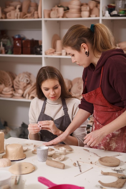 Capture verticale d'une potière enseignant à une jeune femme travaillant avec de l'argile en classe d'art