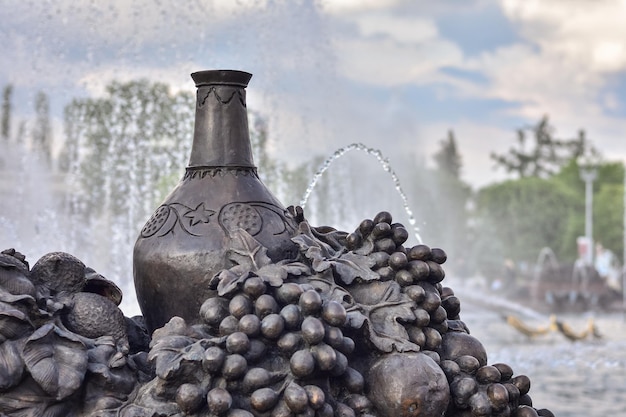 Carafe en bronze et raisins à la fontaine
