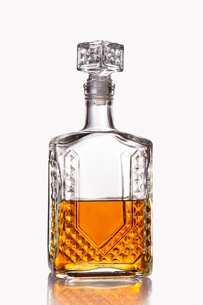 Carafe en verre à moitié remplie de cognac ou autre boisson alcoolisée isolée