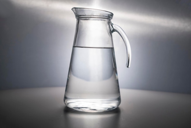 Une carafe en verre remplie d'eau potable propre magnifiquement illuminée sur fond gris Publicité sur l'eau L'eau c'est la vie L'espace pour le texte CopySpace aucun sujet de prise de vue