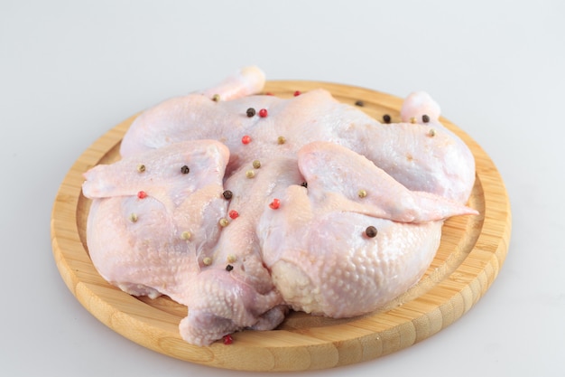 Carcasse de poulet cru sur la planche à découper isolé sur blanc