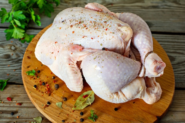 Carcasse de poulet cru prêt pour la cuisson sur une planche à découper sur fond de bois.