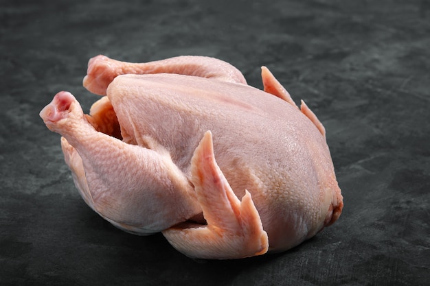 Carcasse de poulet frais sur fond gris, viande fraîche, espace de copie, photo pour les épiceries. fond sombre.