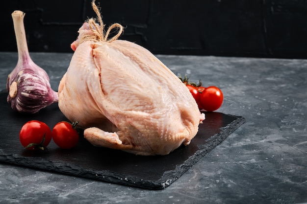 Carcasse de poulet frais sur une viande grise et fraîche, espace copie, photo pour les épiceries. sombre