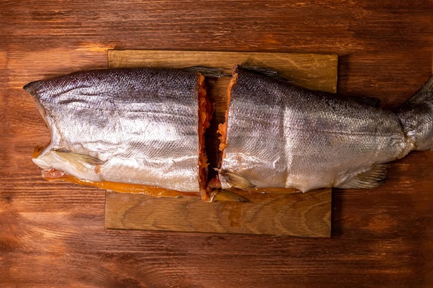 Carcasse de saumon coupée en deux sur une planche à découper en bois