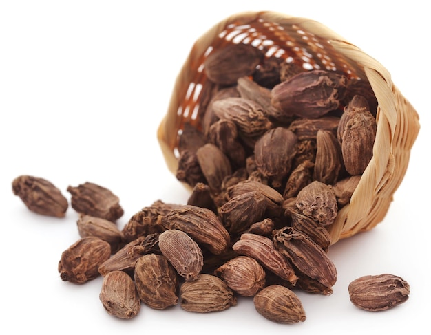 Cardamome noire dans un panier sur fond blanc