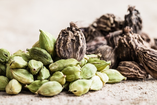 Cardamome noire et verte, graines entières sur bois