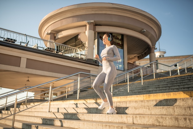 Cardio. Fit girl in sportswear gris s'échauffant cardio dans les escaliers